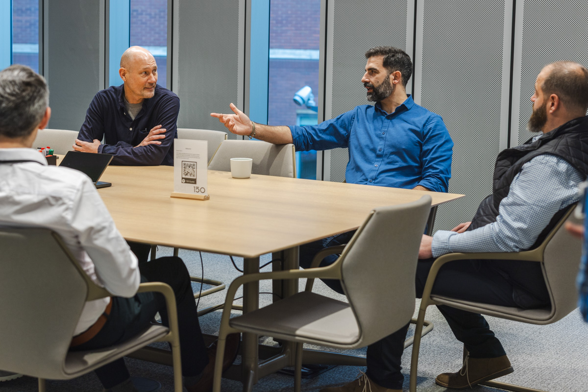 4 people having a lively discussion in a meeting room at 150 Holborn, highlighting Ideal's Smart Building Consultancy services.