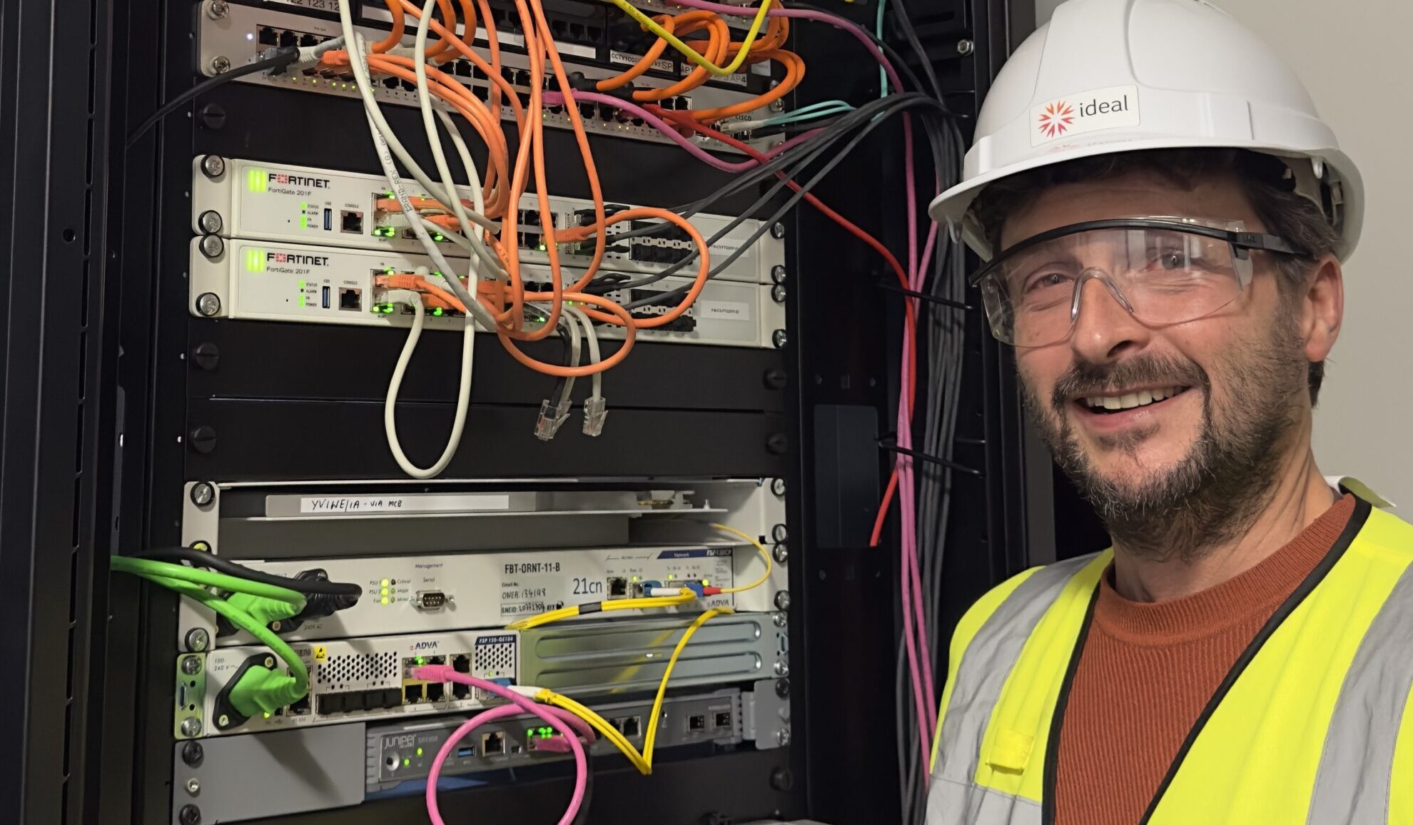 Engineer with hard hat and glasses beside an electronics counter, highlighting Ideal's Professional Services