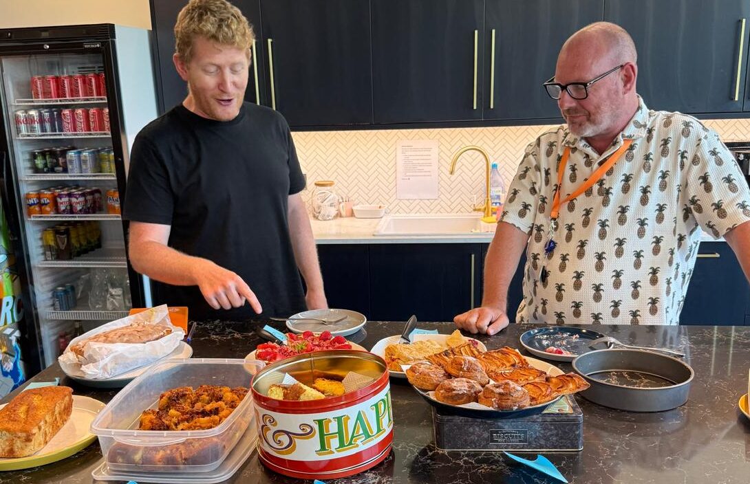 Tim and Pat judging homemade cakes in the Ideal offices, during the bake-off challenge.