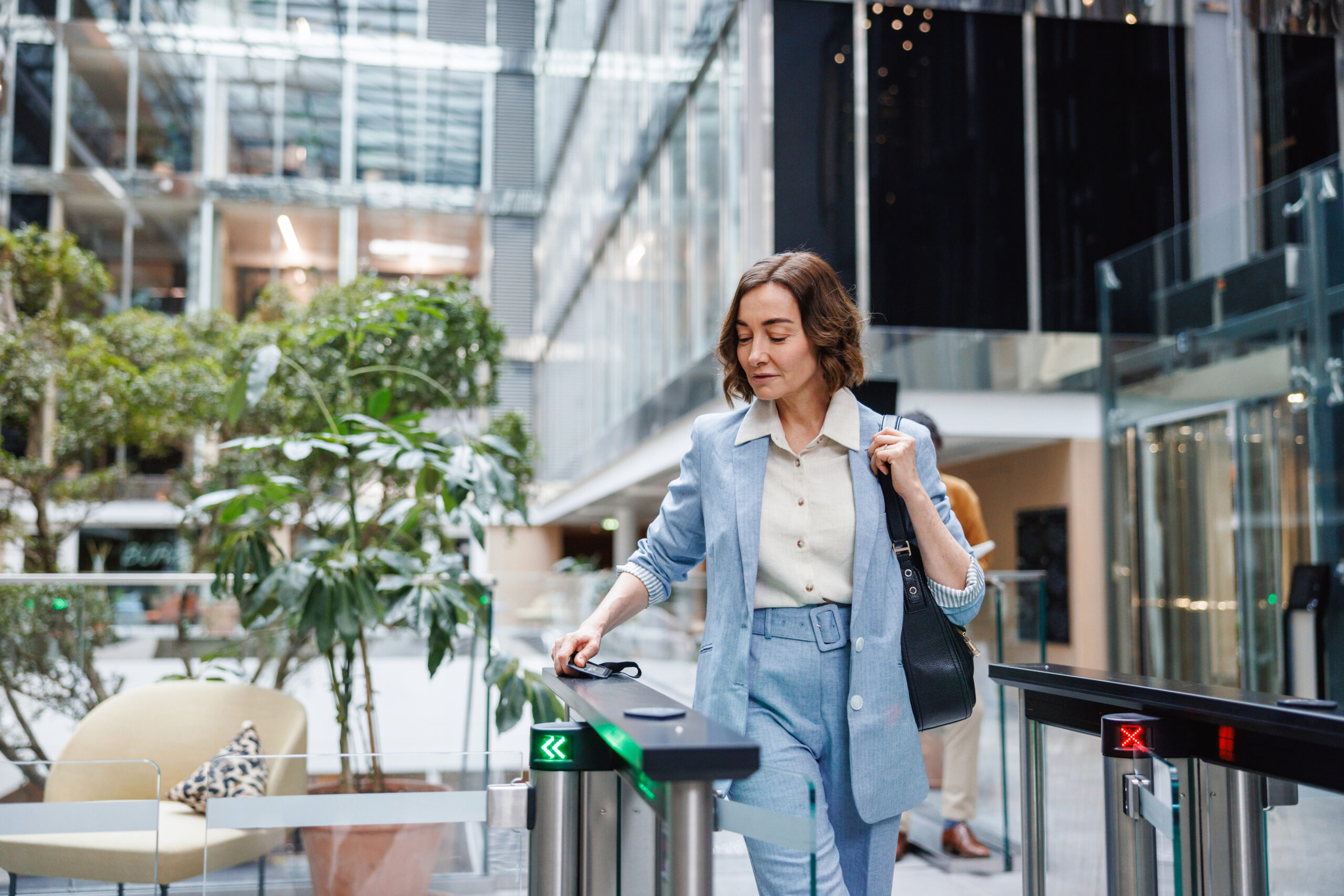 Business woman in a blue suit checks through a security gate highlighting Perimeter Security from Ideal.