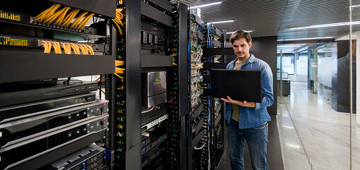 Thin crop of computer engineer fixing an outage in the server room of a corporate office using his laptop computer
