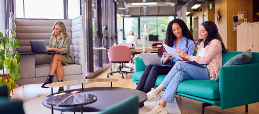 Thin crop of businesswomen Having Informal Meeting In Breakout Seating Area Of Modern Office